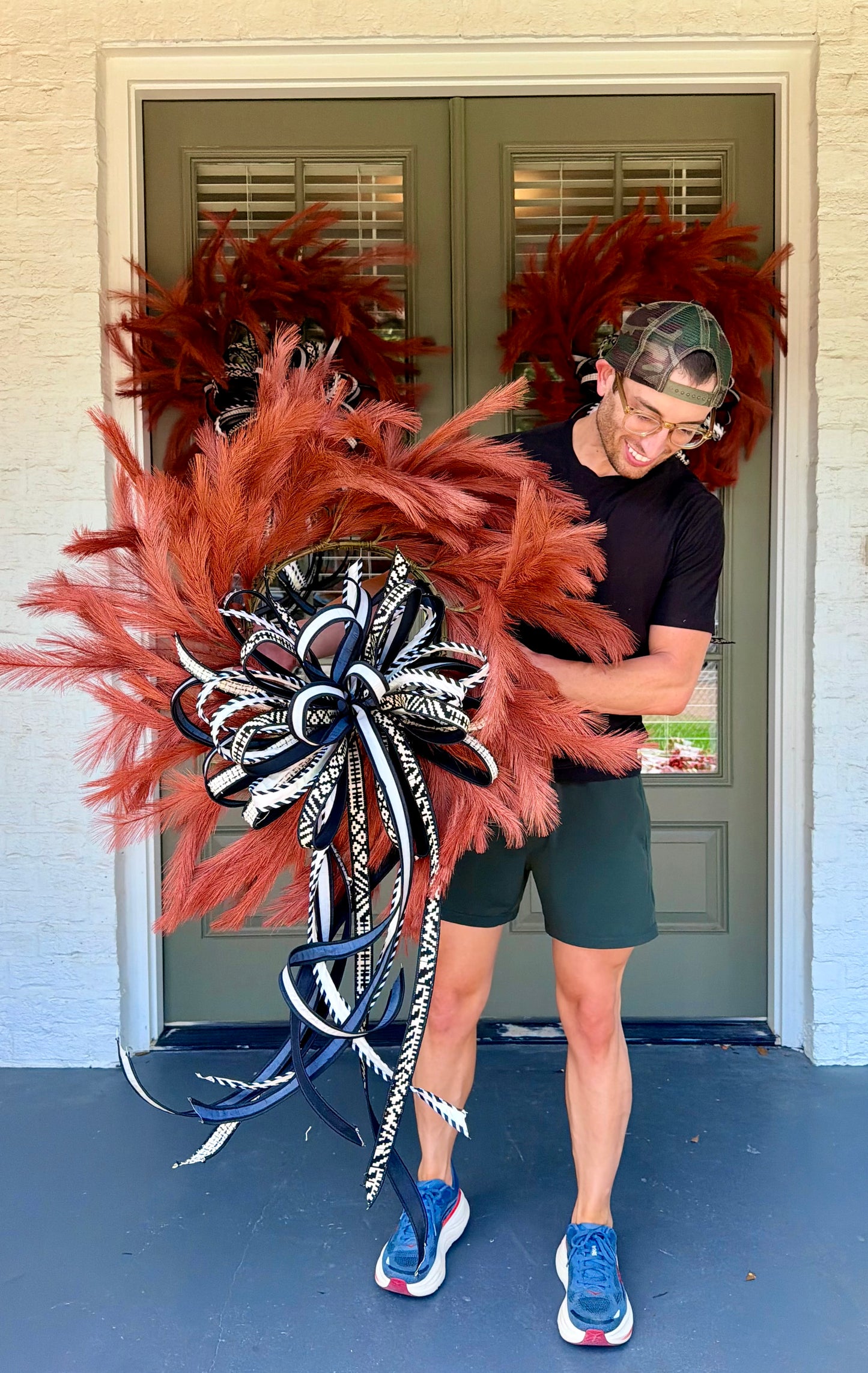 Orange faux plume wreath paired with a hand tied JME bow of black and white 1inch ribbons. About 26 inches in diameter. * some fluffing may be required upon receiving.