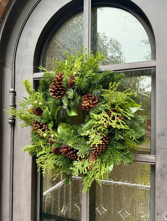 Faux Mixed Foliage Winter Wreath with juniper berries, and pinecones. Perfect to add to any window door or space throw a bow on it and you are good to go! 24 inches wide.