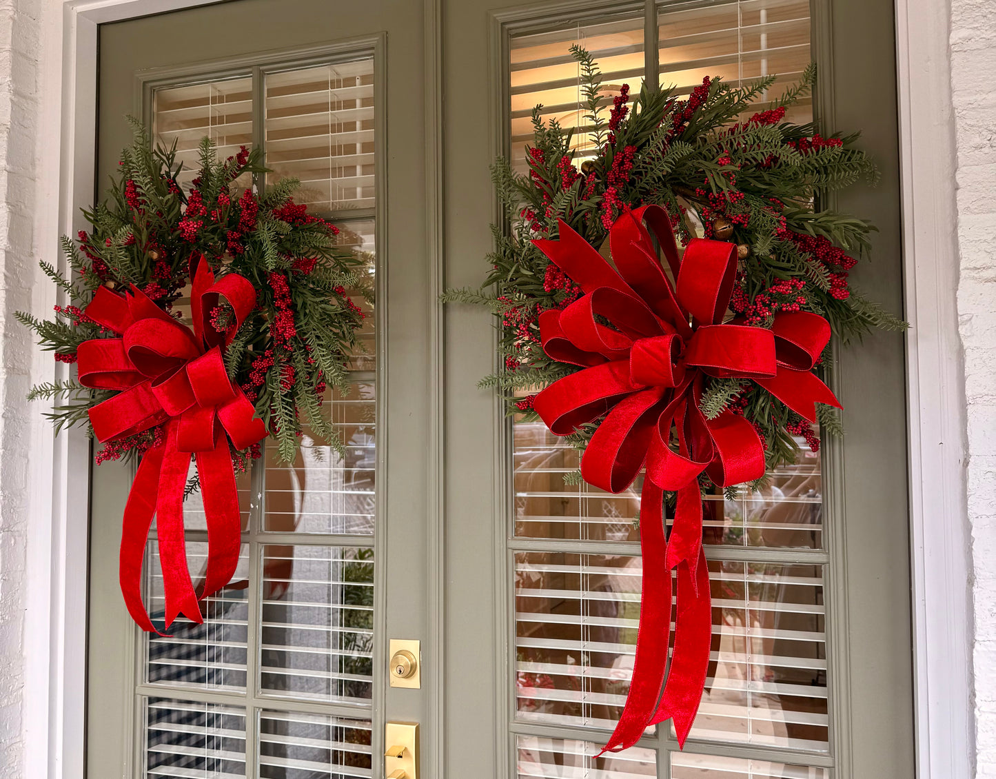 Jingle bell and faux berry wreath. Tied with a JME red velvet bow. About 24 inches wide.