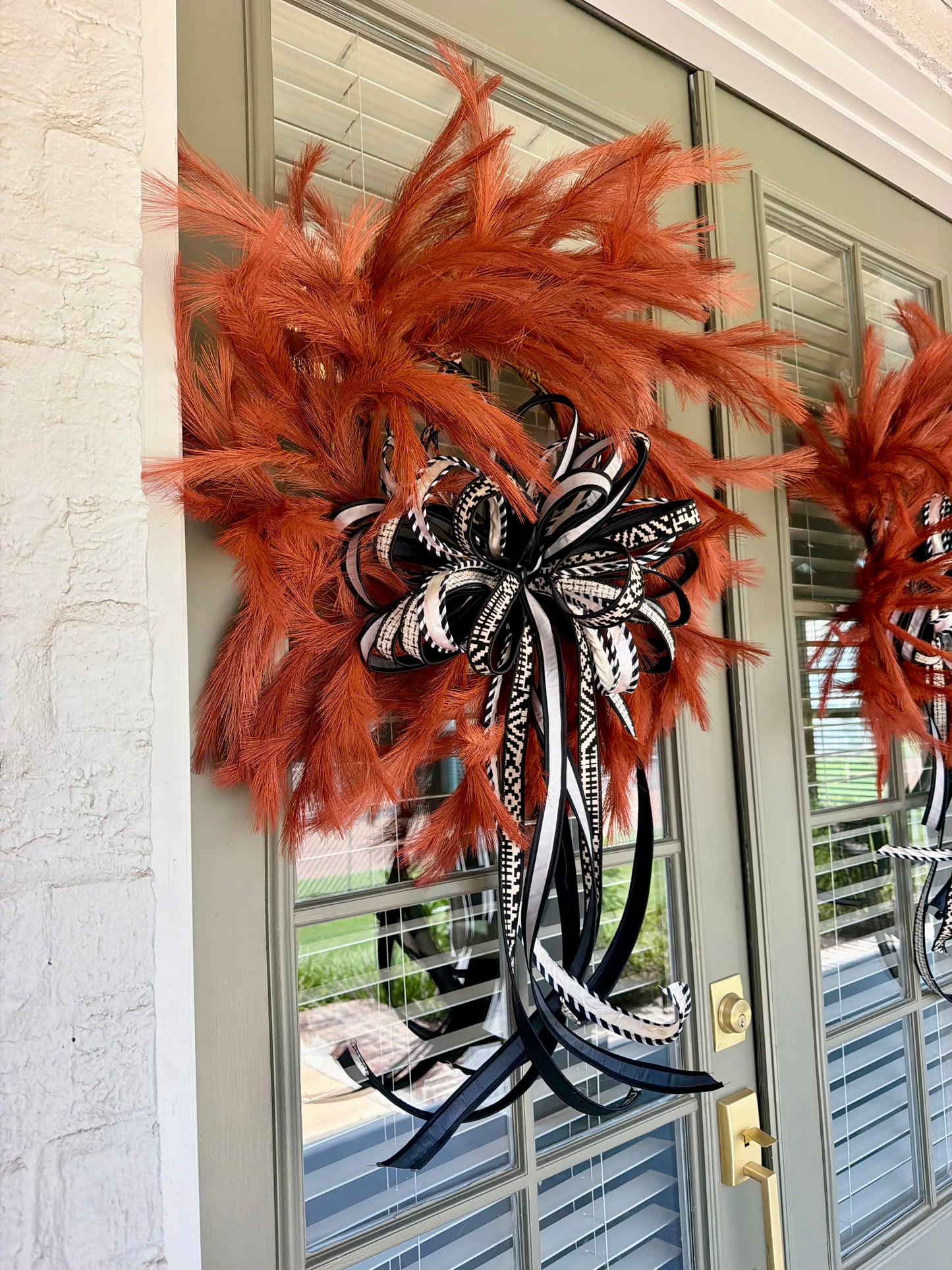 Orange faux plume wreath paired with a hand tied JME bow of black and white 1inch ribbons. About 26 inches in diameter. * some fluffing may be required upon receiving.