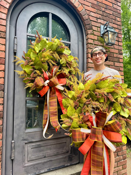 JME HANDMADE WREATH. Magnolia leaves with fall wheat and paired with a JME plaid bow. About 32 inches wide. *Some fluffing may be required upon receiving.
