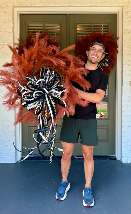 Orange faux plume wreath paired with a hand tied JME bow of black and white 1inch ribbons. About 26 inches in diameter. * some fluffing may be required upon receiving.