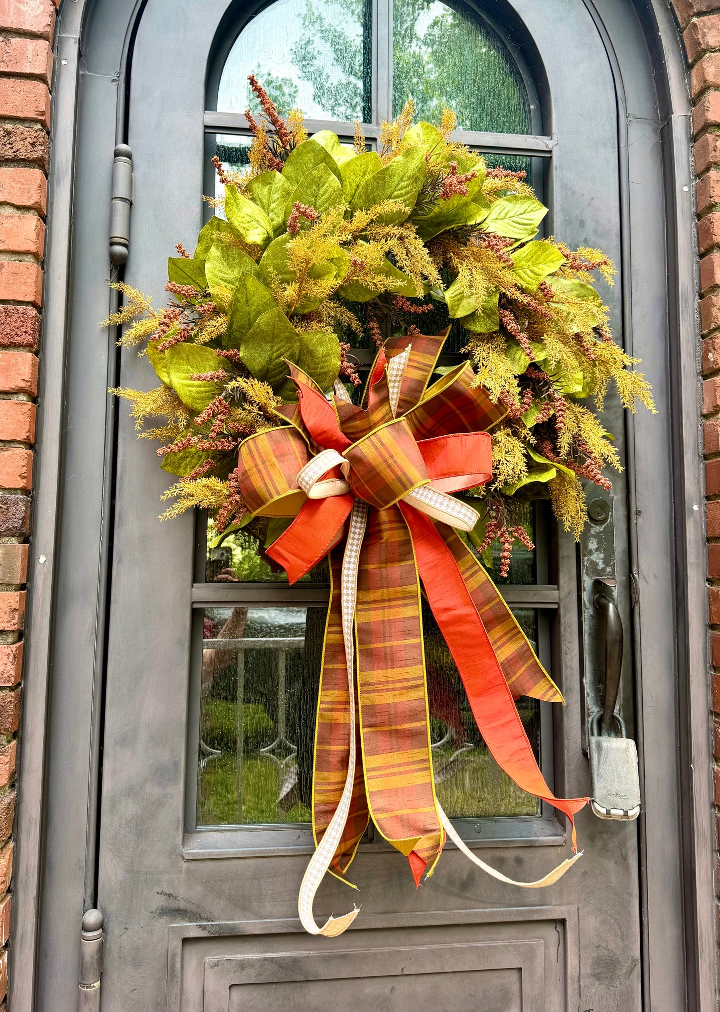 JME HANDMADE WREATH. Magnolia leaves with fall wheat and paired with a JME plaid bow. About 32 inches wide. *Some fluffing may be required upon receiving.