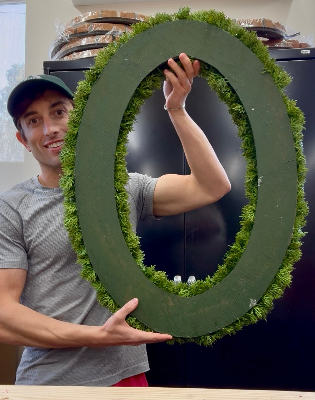 Oval frosted faux cedar wreath. 23inches wide by 30.5 inches long