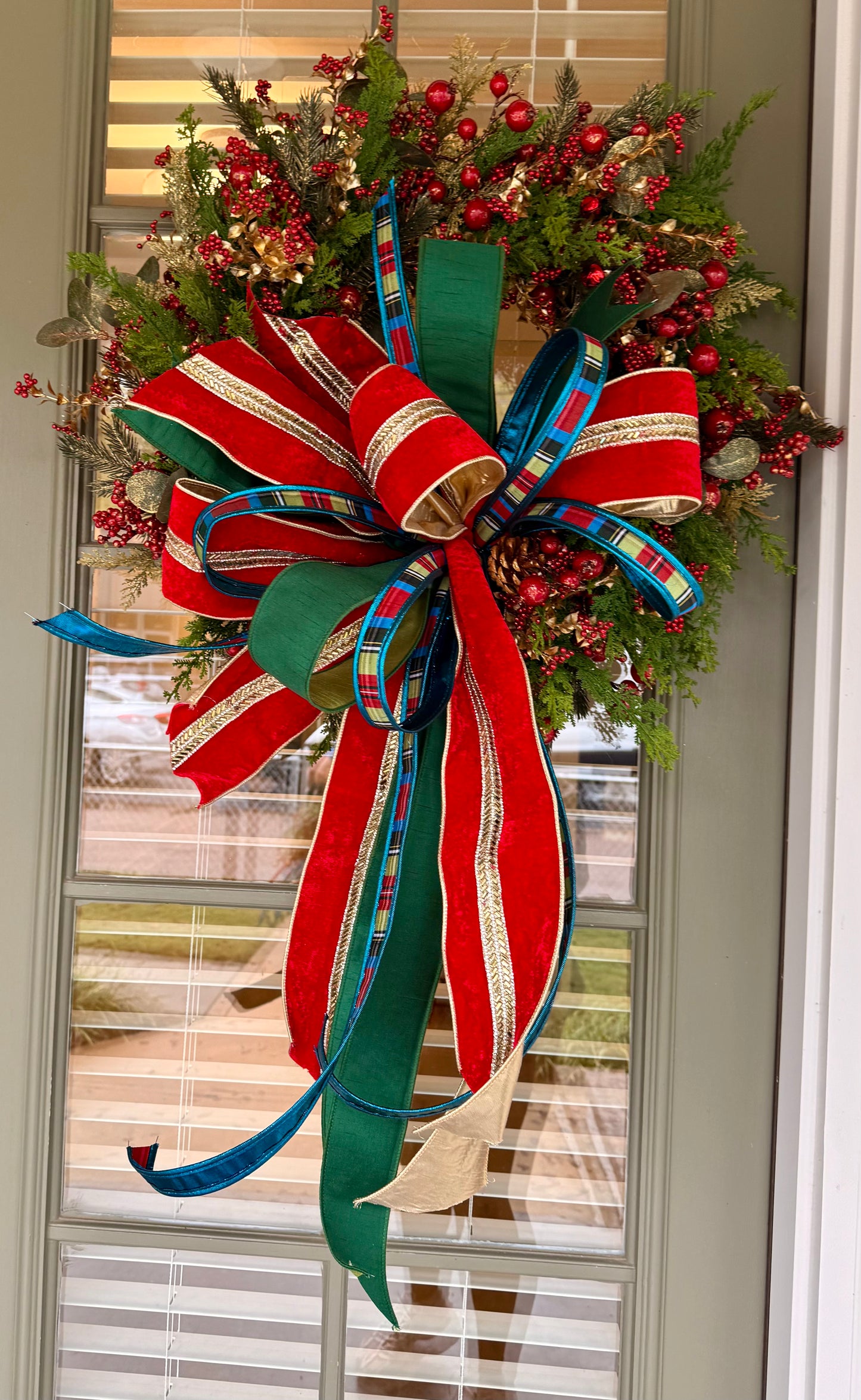 Red jingle bell JME handmade wreath with a JM nutcracker inspired bow. About 24 inches wide.