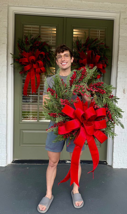 Jingle bell and faux berry wreath. Tied with a JME red velvet bow. About 24 inches wide.
